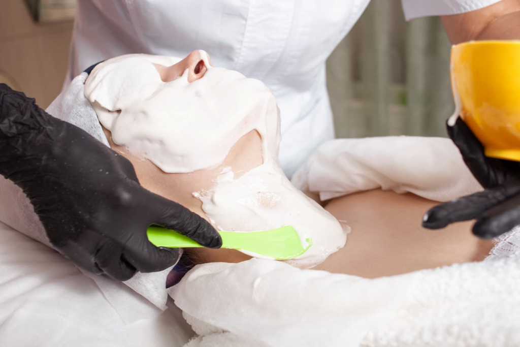 Нанесение альгинатной маски на лицо и шею девушки