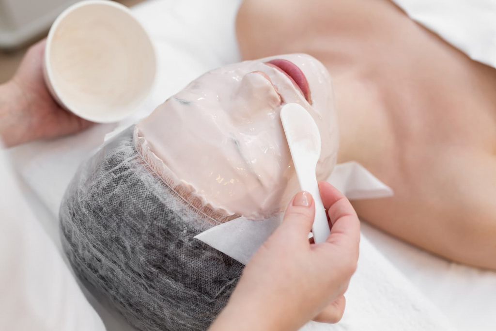 Нанесение альгинатной маски на кожу женщины